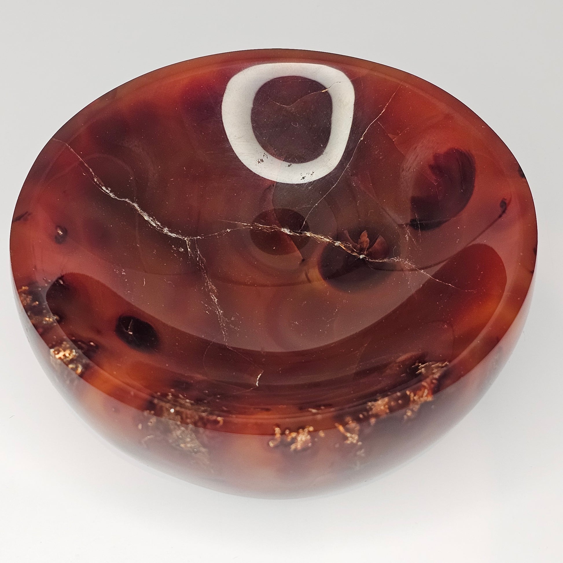 Top-down studio lighting photograph of the dark Carnelian bowl showcasing its glossy finish, natural banding, and rich Madagascan Carnelian colouring.