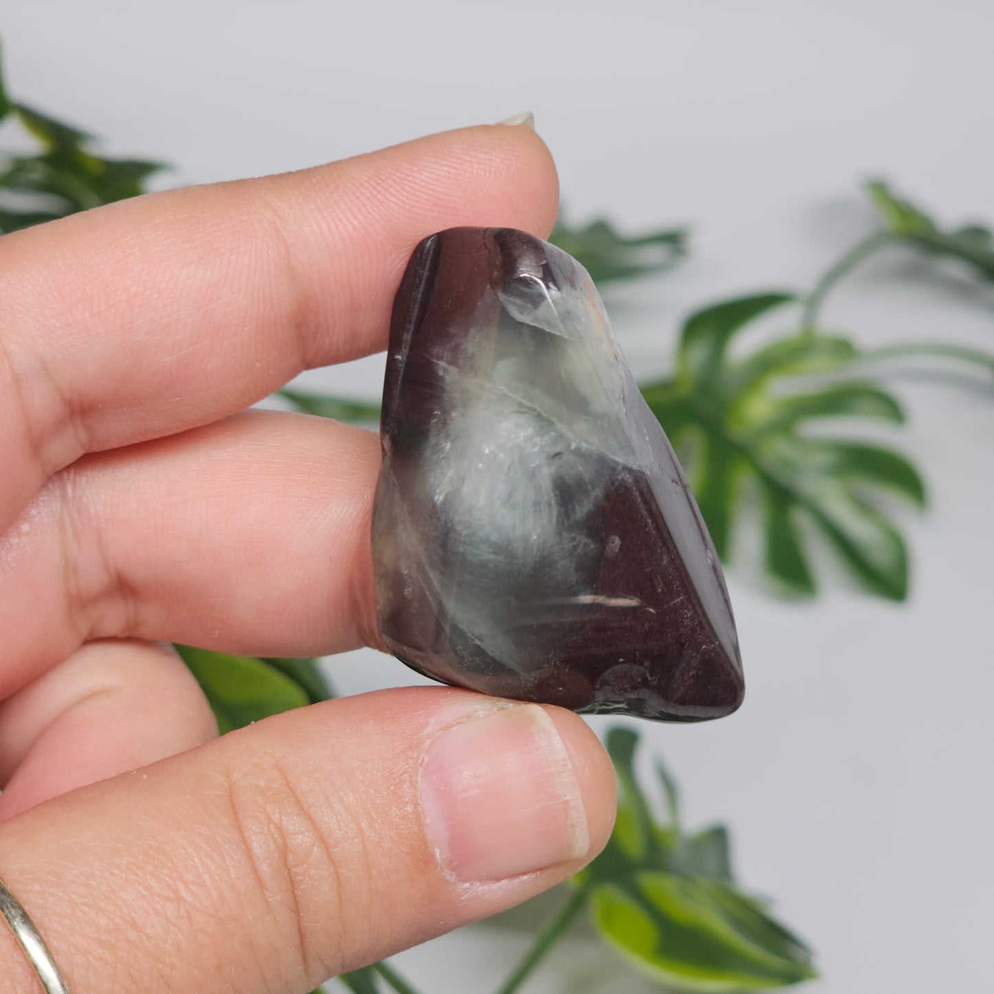 Polished Prehnite slab photographed in hand to show size, translucent green tones, and natural earthy inclusions with a smooth polished finish.