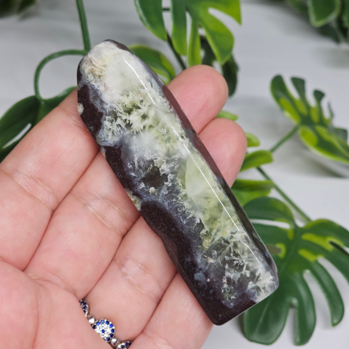 Polished Prehnite slab photographed in hand to show size, translucent green tones, and natural earthy inclusions with a smooth polished finish.