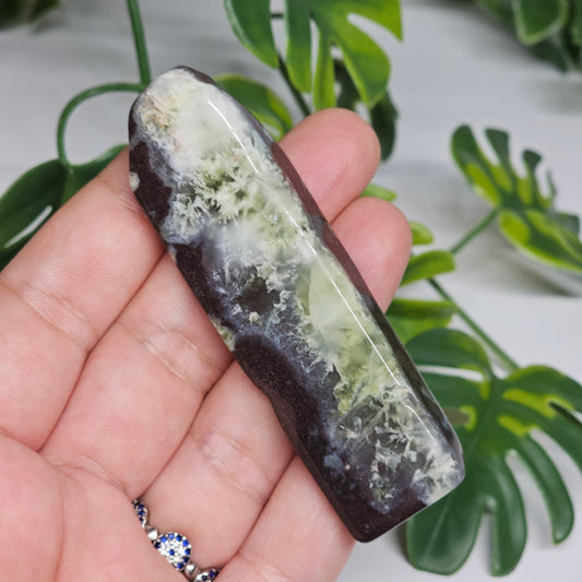 Polished Prehnite slab photographed in hand to show size, translucent green tones, and natural earthy inclusions with a smooth polished finish.