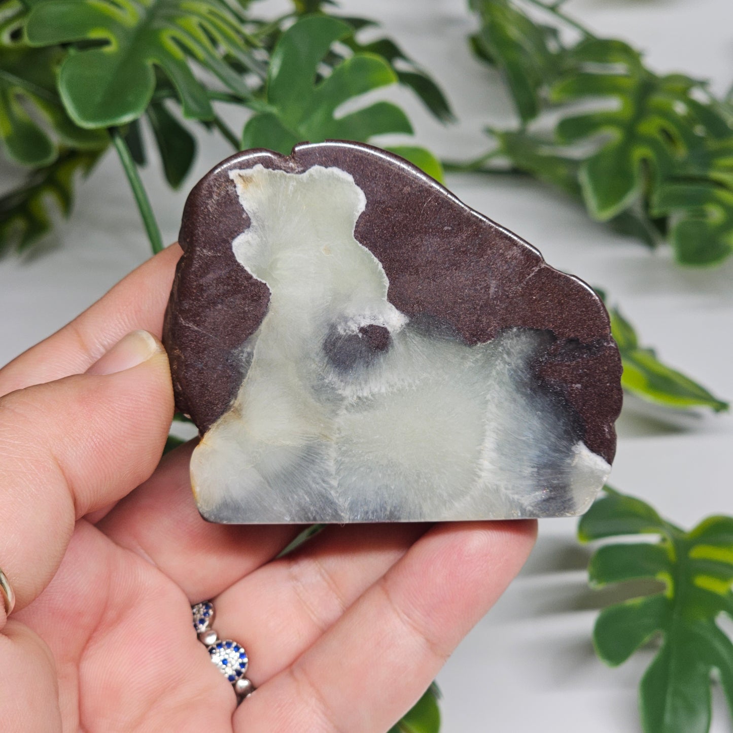 Polished Prehnite slab photographed in hand to show size, translucent green tones, and natural earthy inclusions with a smooth polished finish.