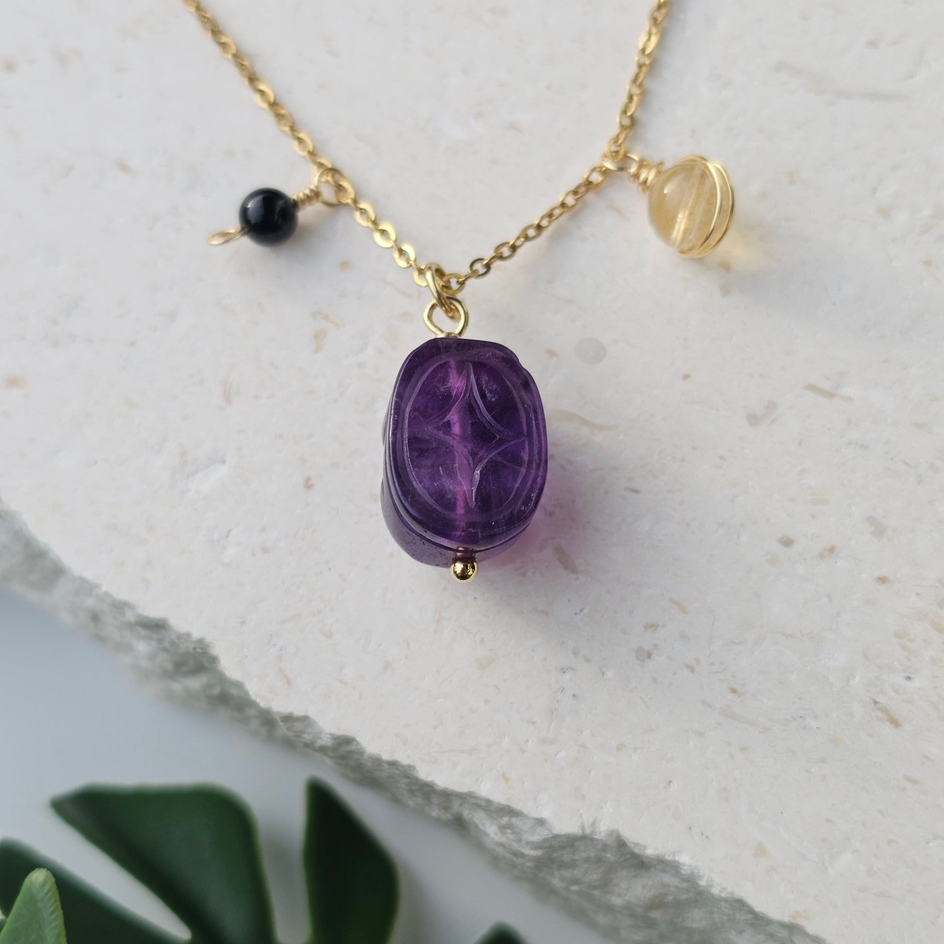 Reverse view of the Protected Prosperity Necklace showing Amethyst Pixiu with Citrine and Black Tourmaline beads splayed to display detail and craftsmanship