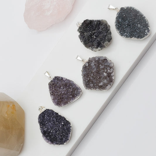 Group of five Rainbow Amethyst cluster pendants showing dark purple to black tones with natural variation and unique crystal formations.