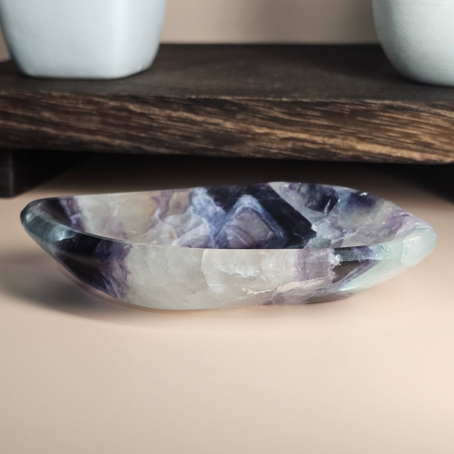 Side view of the dish on a flat surface showing its smooth polished edges and layered white, purple, blue, and green colouring.