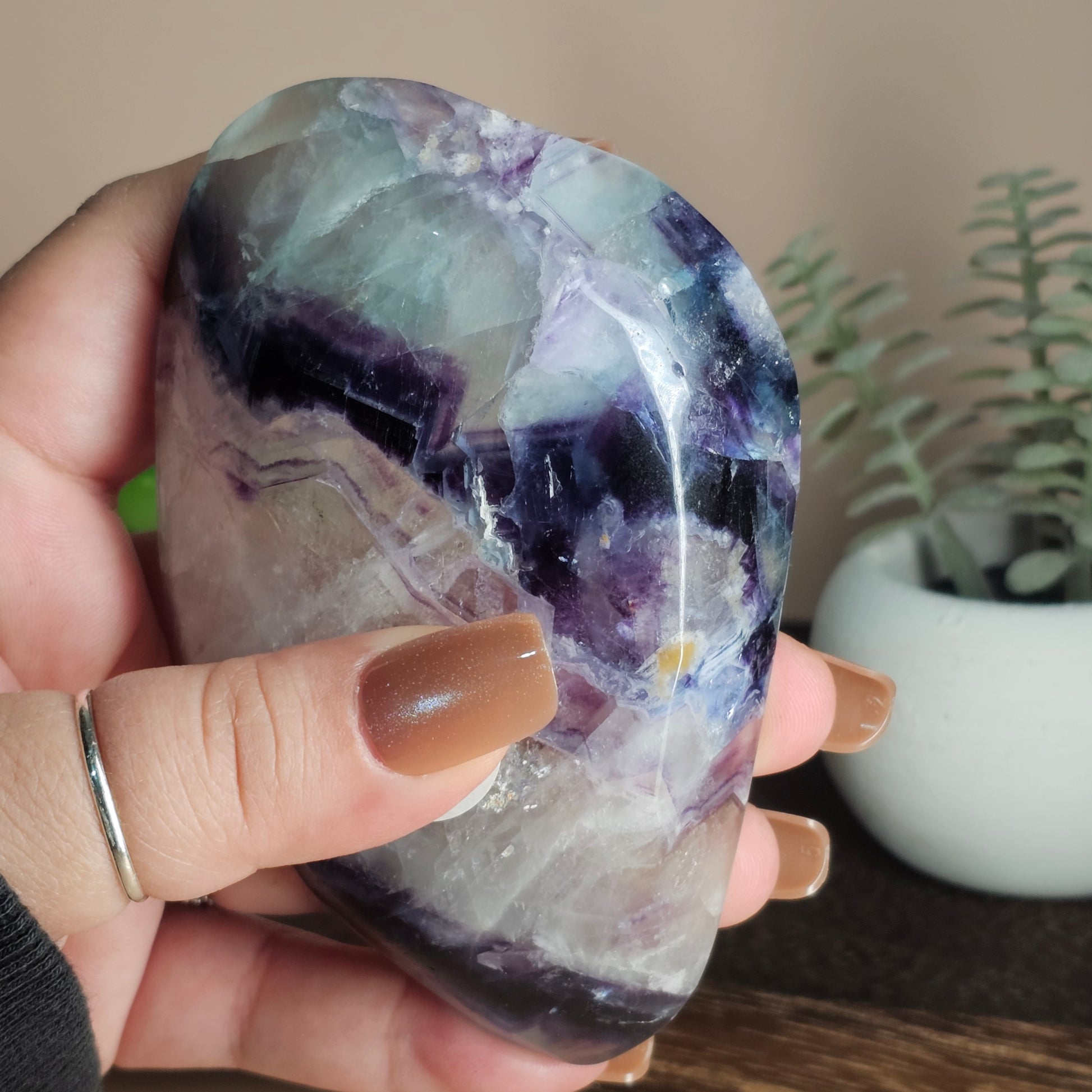 Underview of the Fluorite dish held in hand, highlighting its translucent structure and layered colour zones of white, purple, blue, and green.
