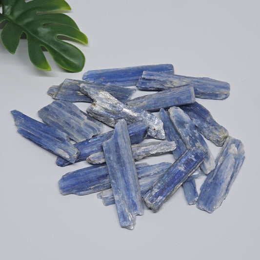Raw Blue Kyanite pieces displayed on a flat surface, showing natural variation in shape, colour, and texture