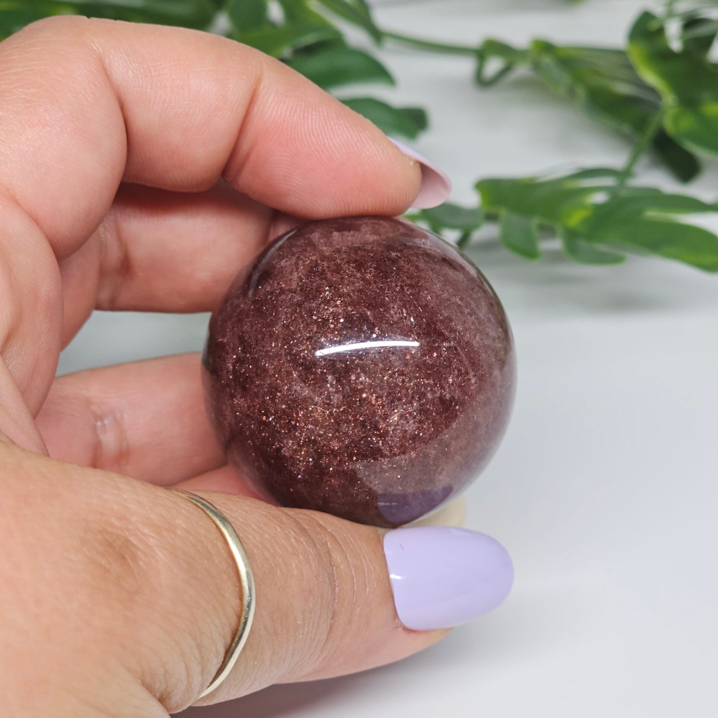 Red Aventurine sphere held in hand showing size, deep colouring and natural sparkle inclusions