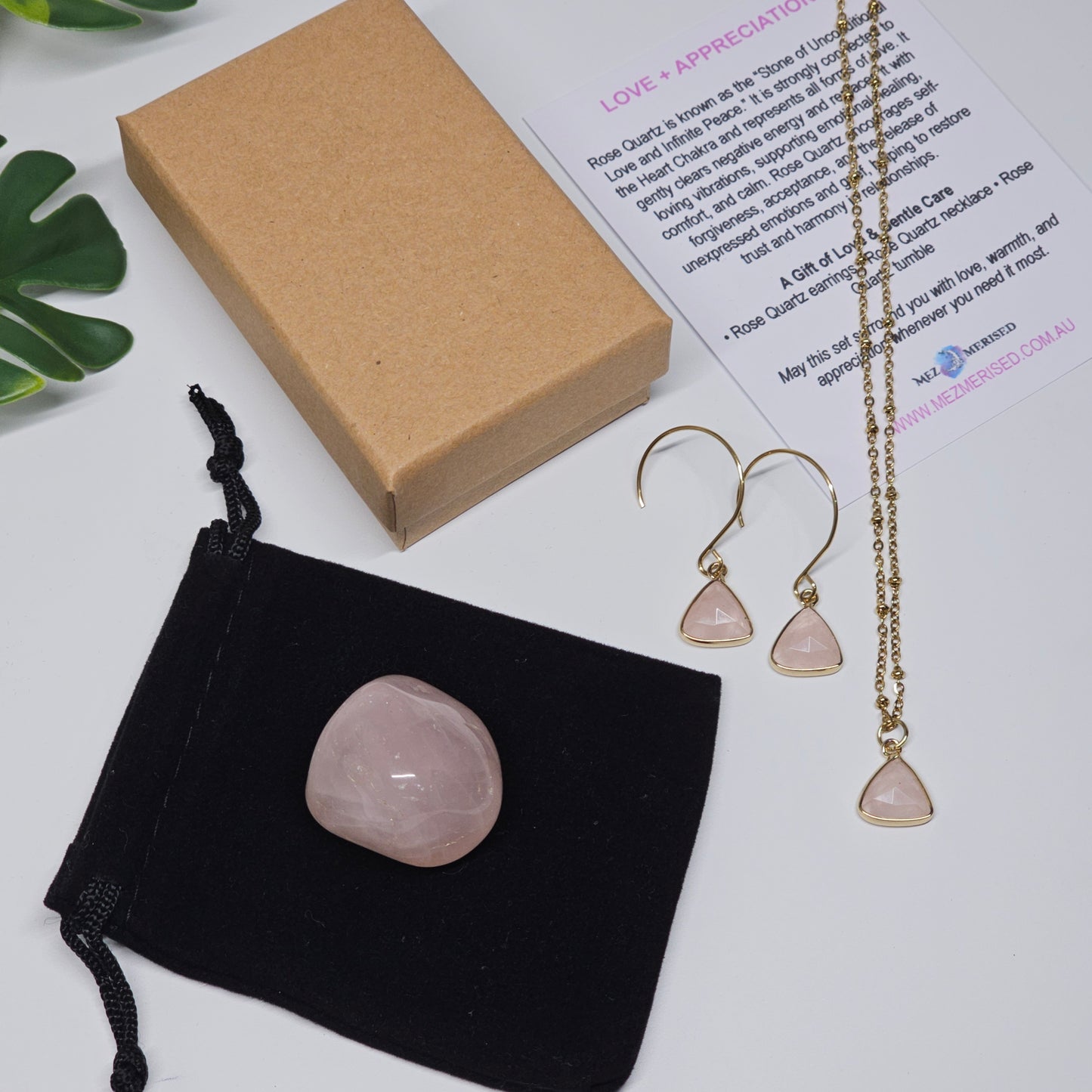 Rose Quartz set with necklace, earrings, tumble stone, velvet pouch and information card laid out together.