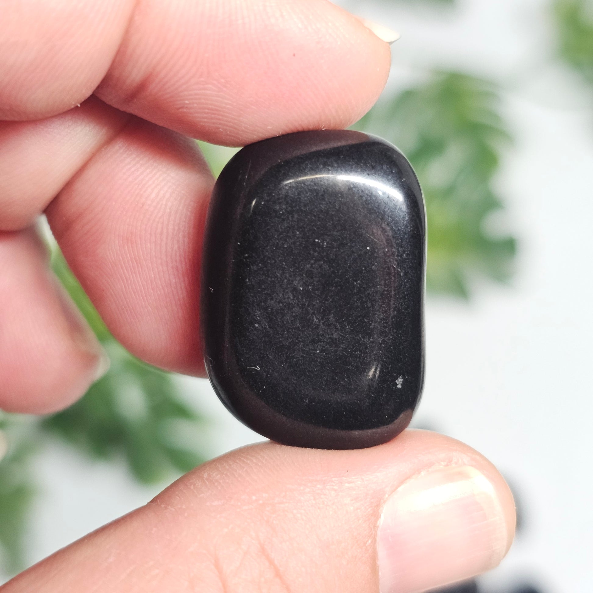 A single small Black Tourmaline tumble held in hand, perfect for carrying as a personal grounding and protective stone.