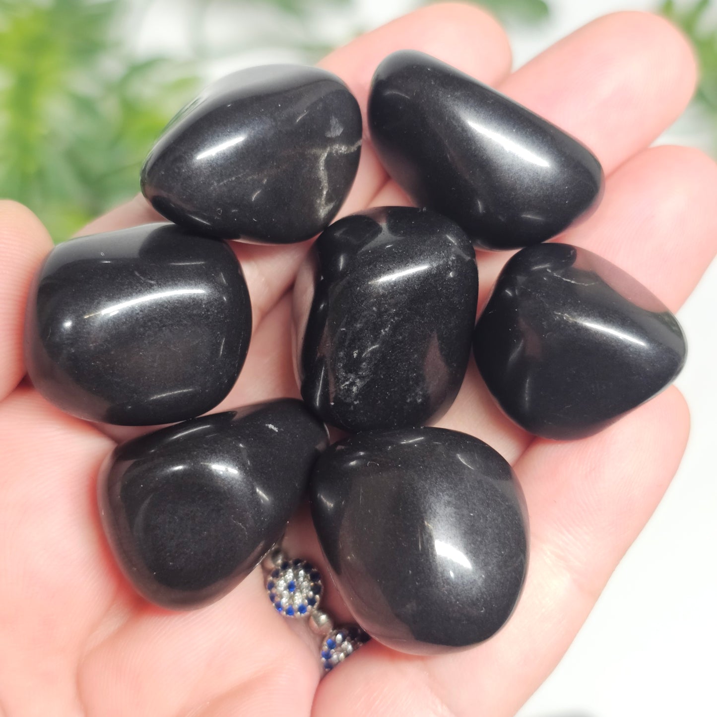 Small Black Tourmaline tumble stones held in hand, showing their deep black colour and strong grounding, protective energy.