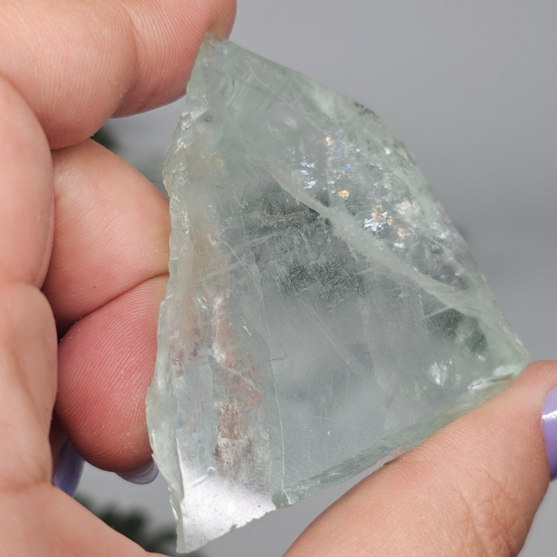 Small Green Fluorite slab tilted to enhance natural internal rainbows and light reflection through the crystal.