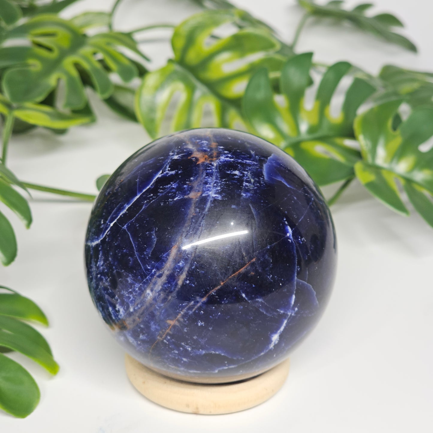 Angled view of Sodalite sphere A on display stand, revealing depth of colour and unique natural marbling.