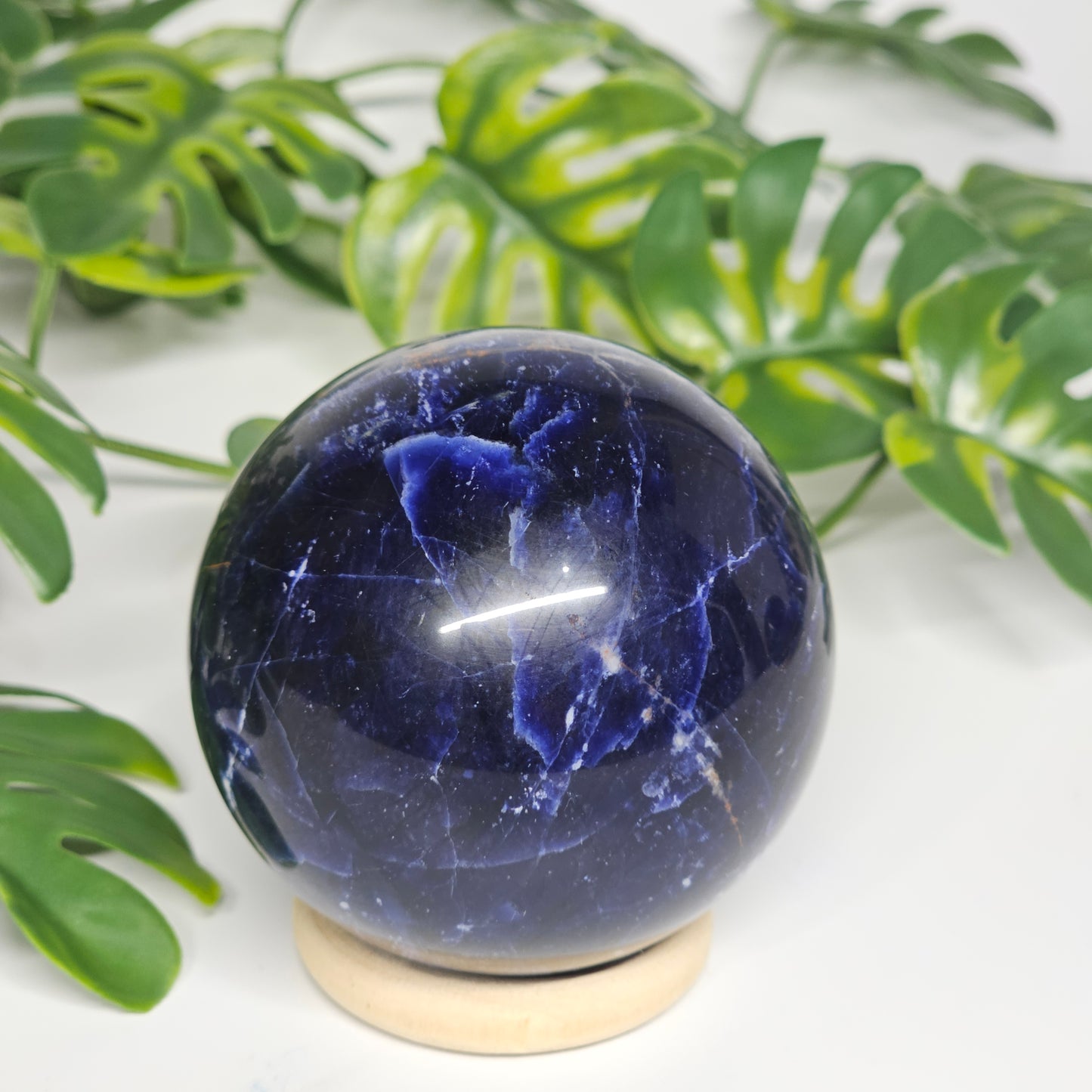 Reverse side of Sodalite sphere A on stand, showcasing its distinct patterning and polished finish.