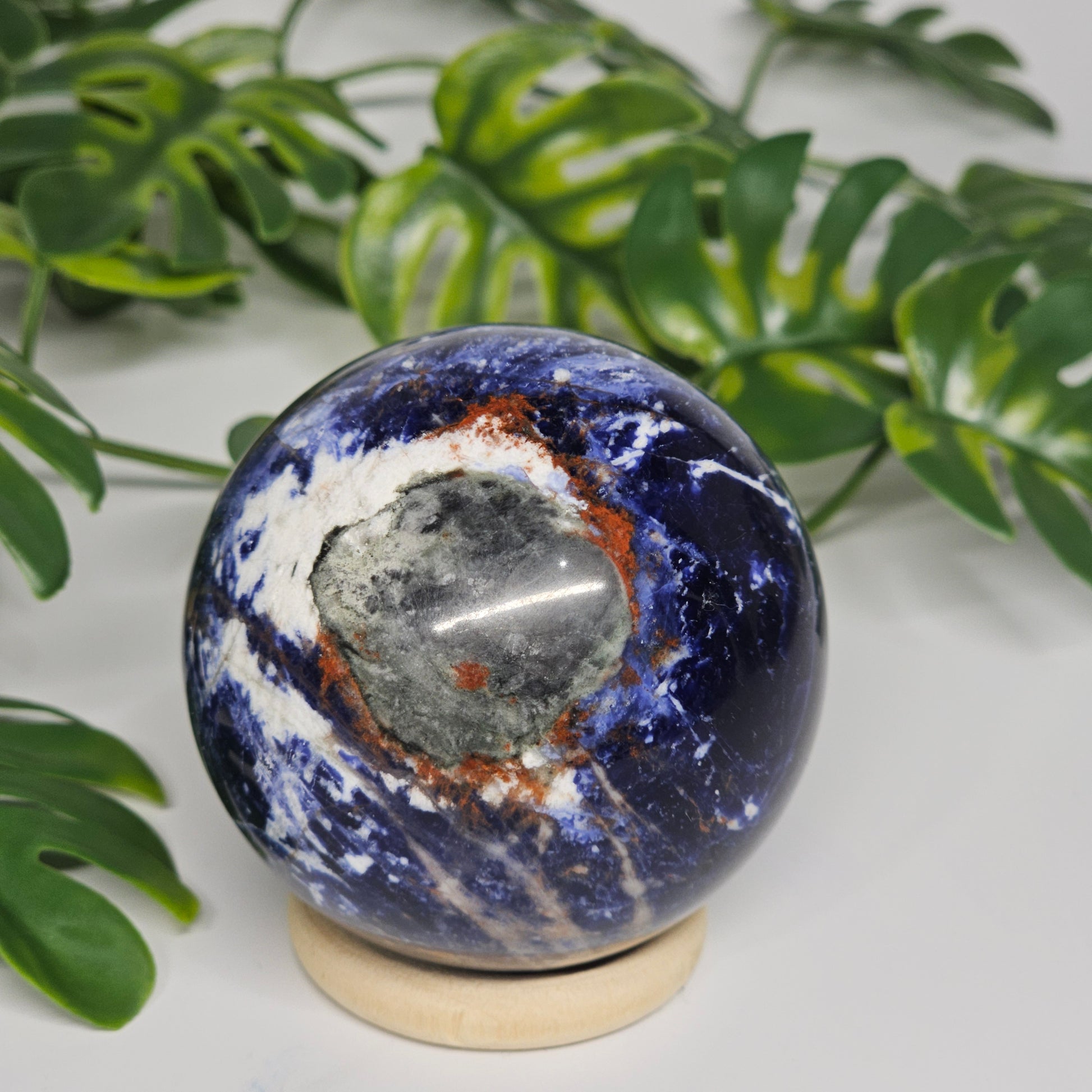 Rotational view of Sodalite sphere A on stand, highlighting natural variations, deep blue tones, and smooth polish.