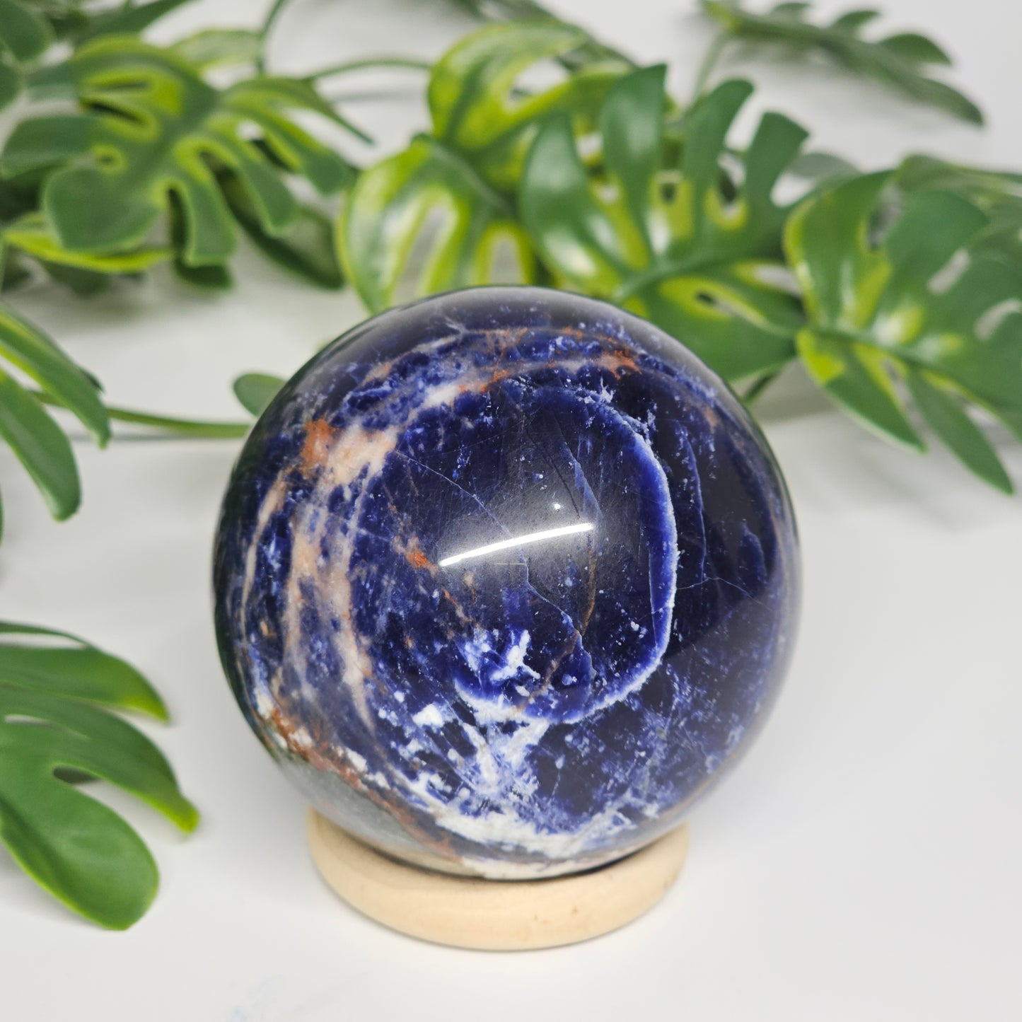 Side view of Sodalite sphere A on its stand, highlighting its polished surface and natural colour variation.