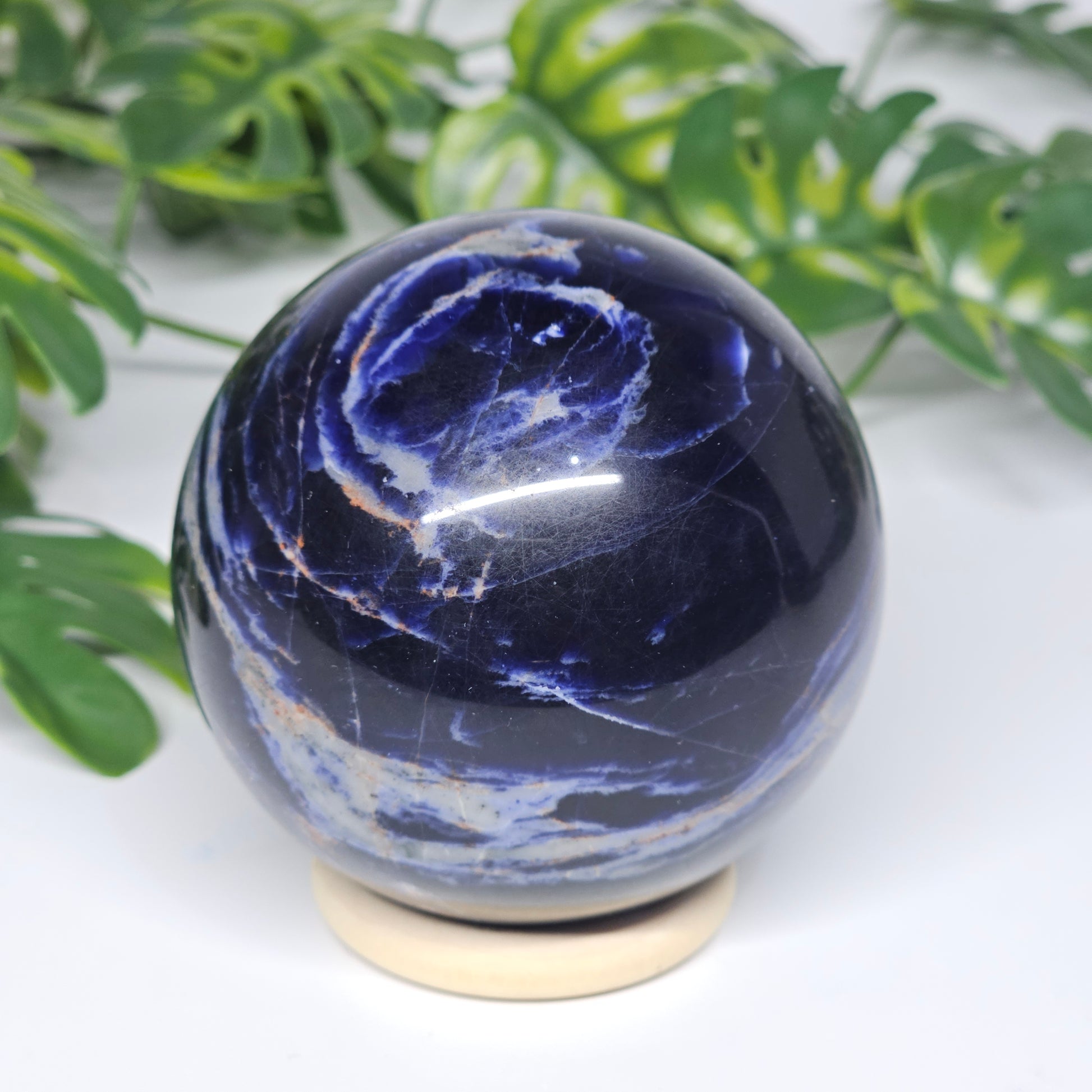 Angled view of Sodalite sphere B on stand, revealing depth of colour and natural grey marbling.