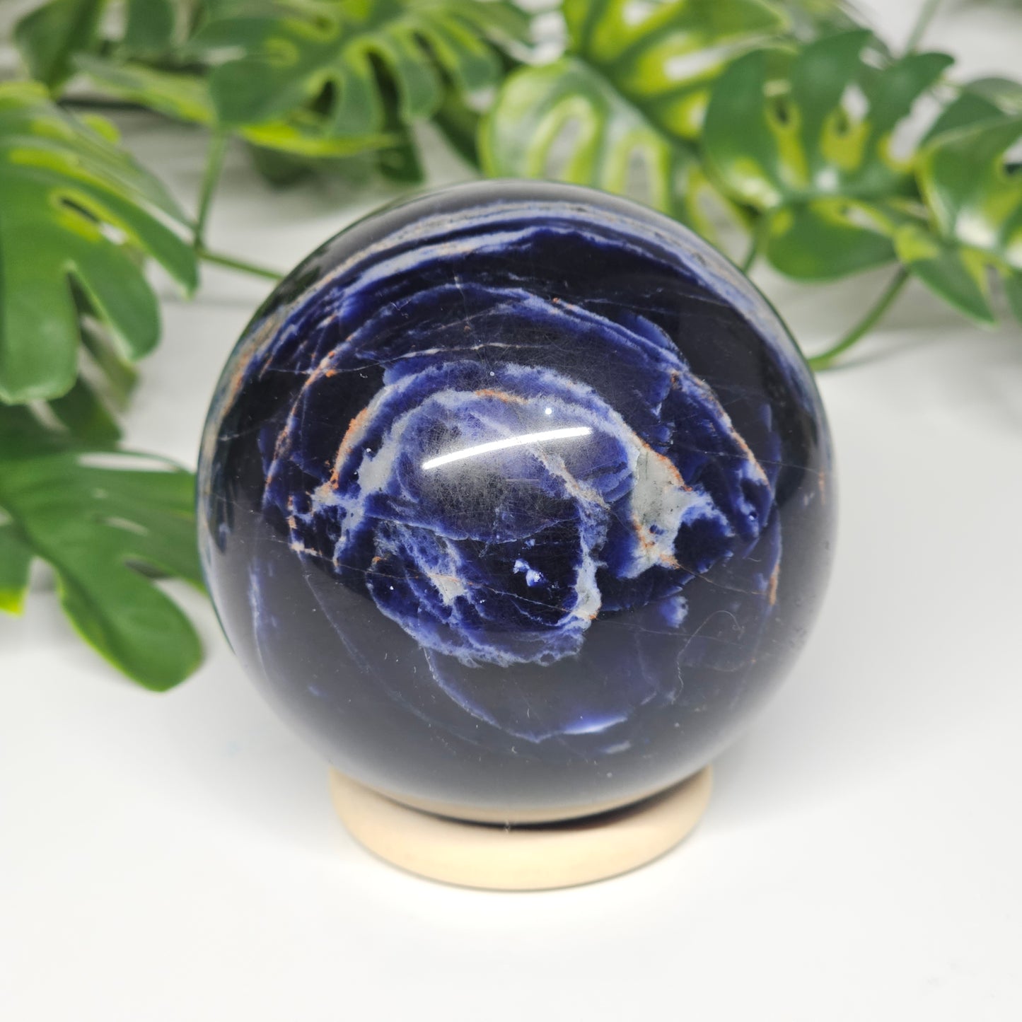 Close-up view of Sodalite sphere B on stand, showing its rich navy blue tones, soft grey marbling, and smooth polished finish.
