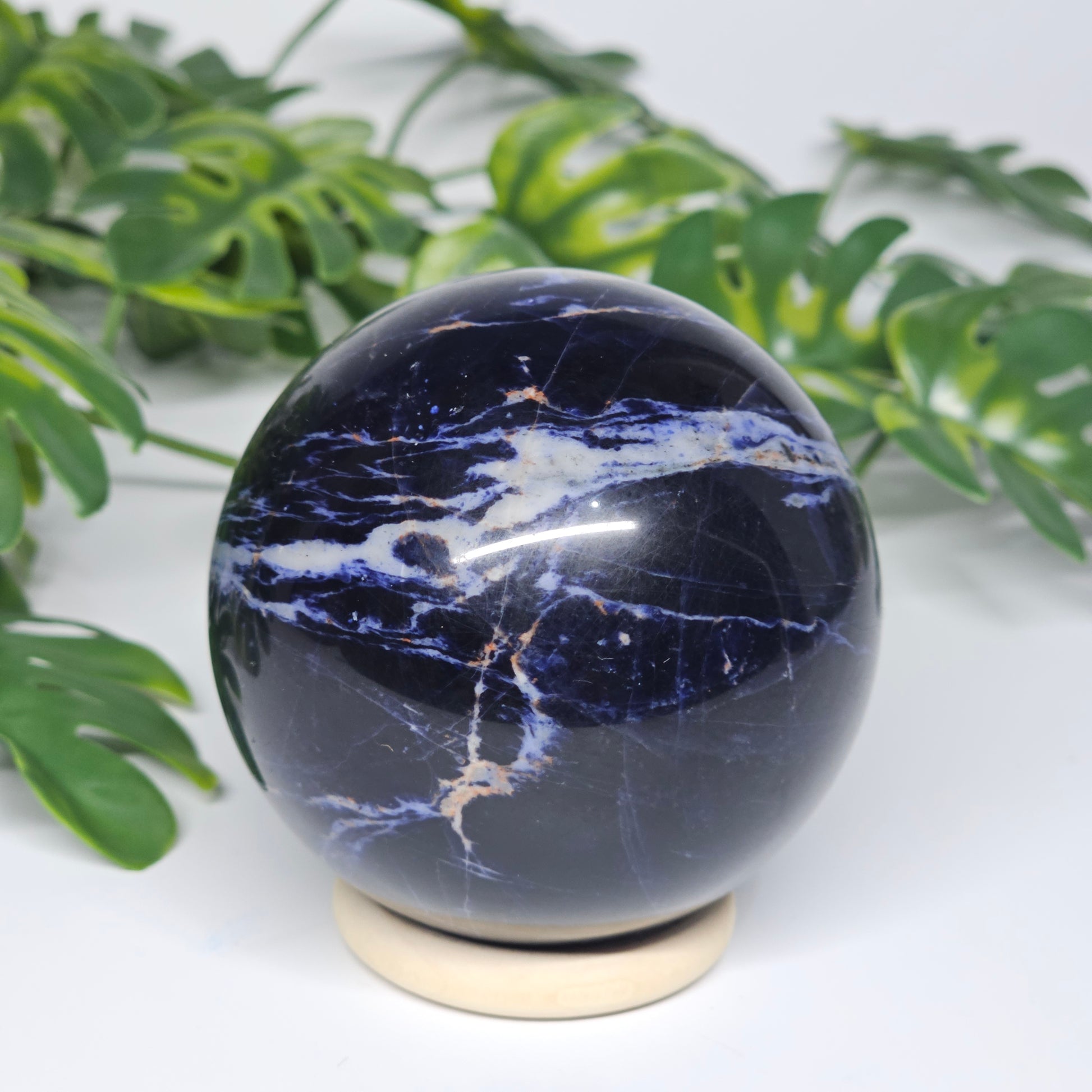 Front view of Sodalite sphere B on display stand, highlighting its dark navy colouring and soft grey veining.