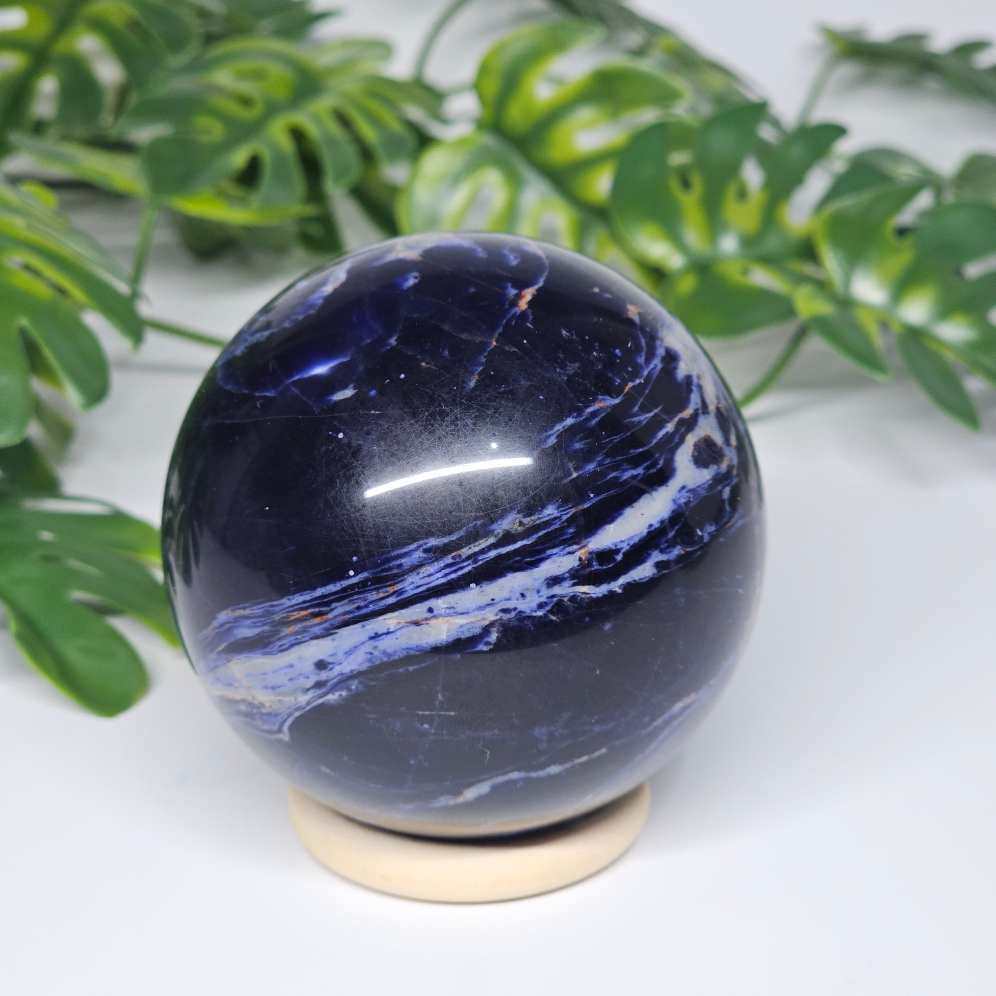 Reverse side of Sodalite sphere B on display stand, showcasing its darker navy tones and unique natural patterning.