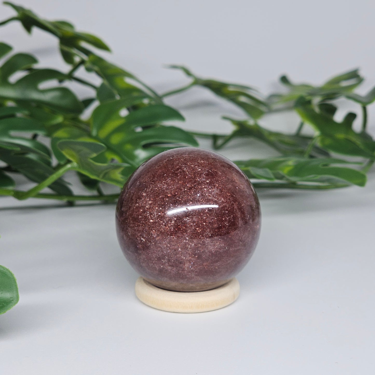 Strawberry Quartz crystal sphere with rich pink-red tones and natural shimmer showing polished reflective surface