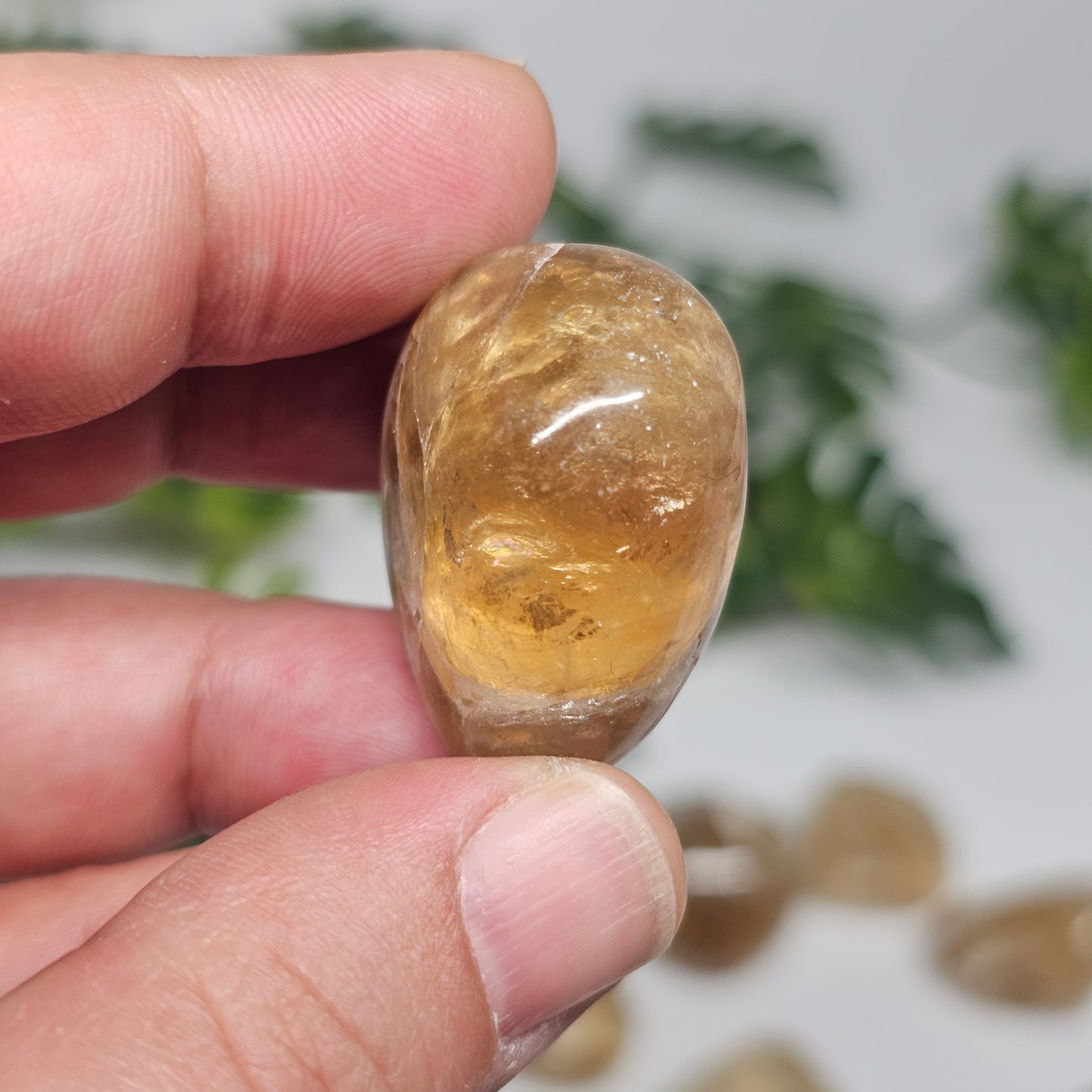 Close-up of a single Topaz tumble stone highlighting its warm golden tone, gentle internal clarity, and smooth polished finish in natural light.