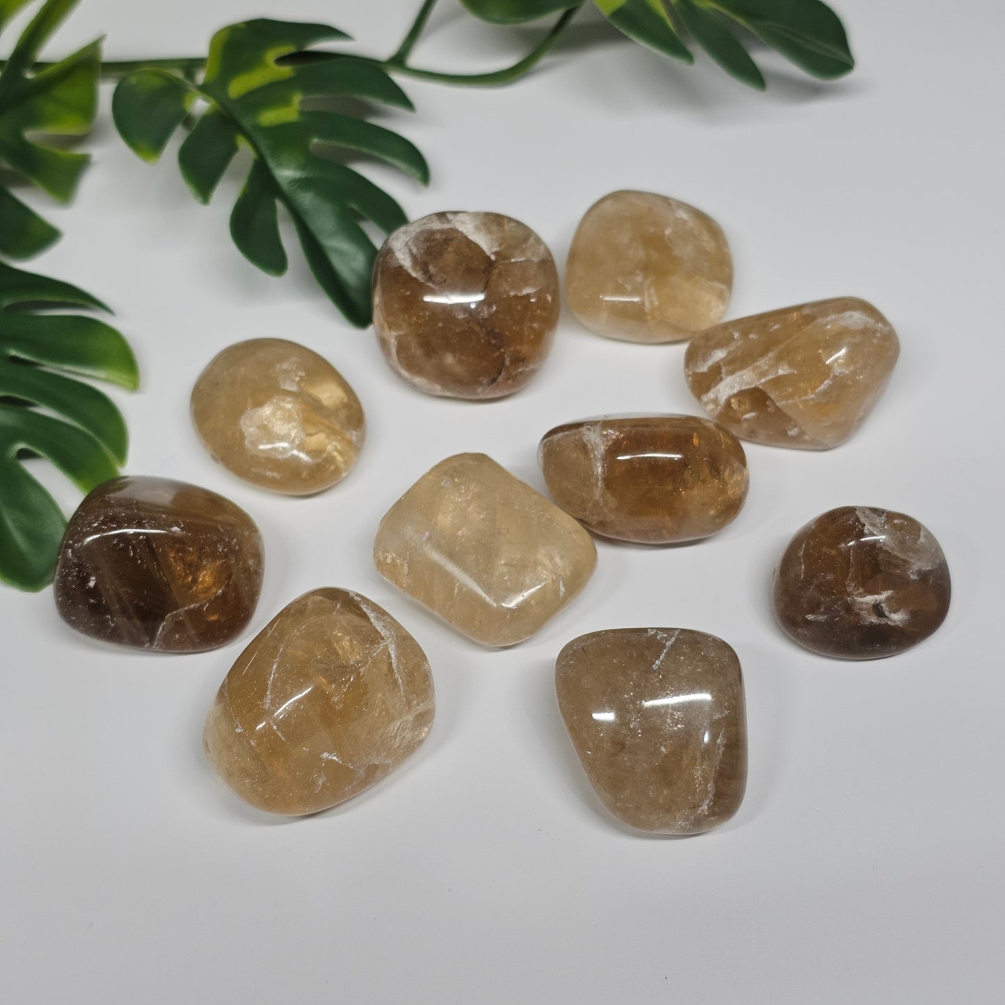 Close arrangement of Topaz tumble stones on a surface, highlighting their natural colour variation from honey gold to soft yellow tones under light.
