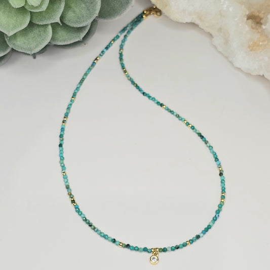 Flat lay view of the 2mm faceted Turquoise bead necklace featuring a CZ round pendant and gold-toned accents, showcasing the full length and balanced design of the piece.