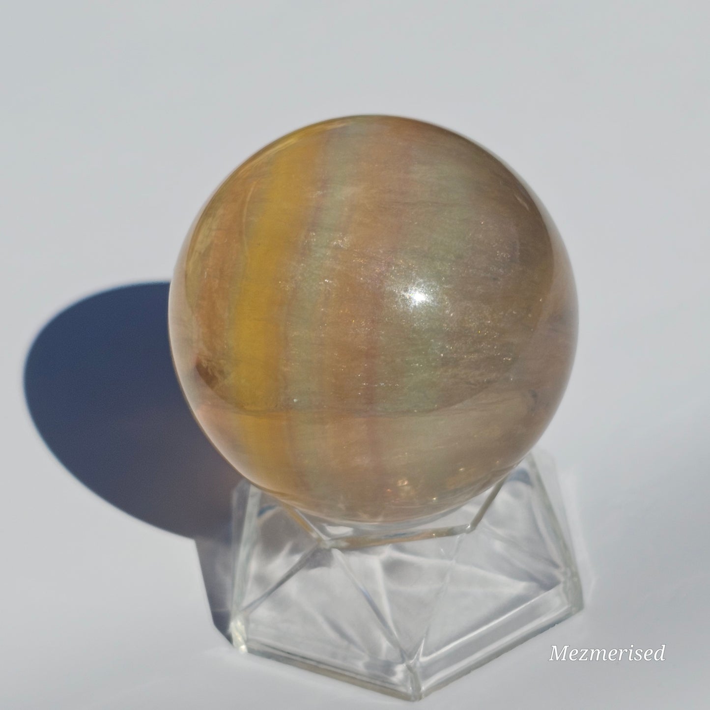 Yellow rainbow Fluorite sphere banded with an array of colours, including a display of beautiful rainbows.