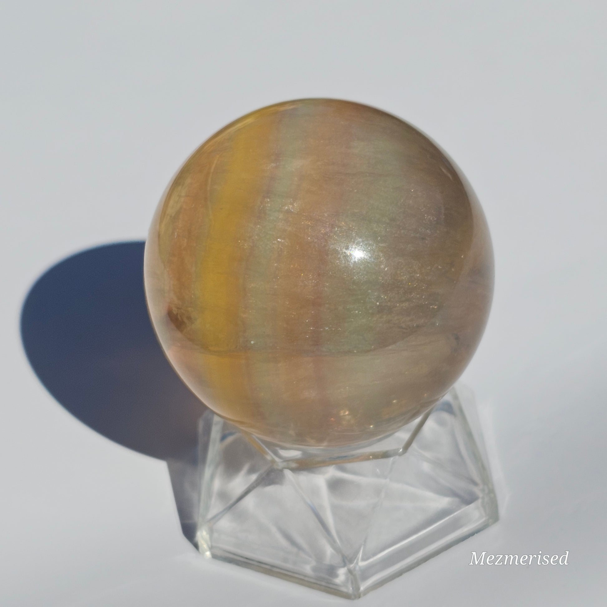 Yellow rainbow Fluorite sphere banded with an array of colours, including a display of beautiful rainbows.