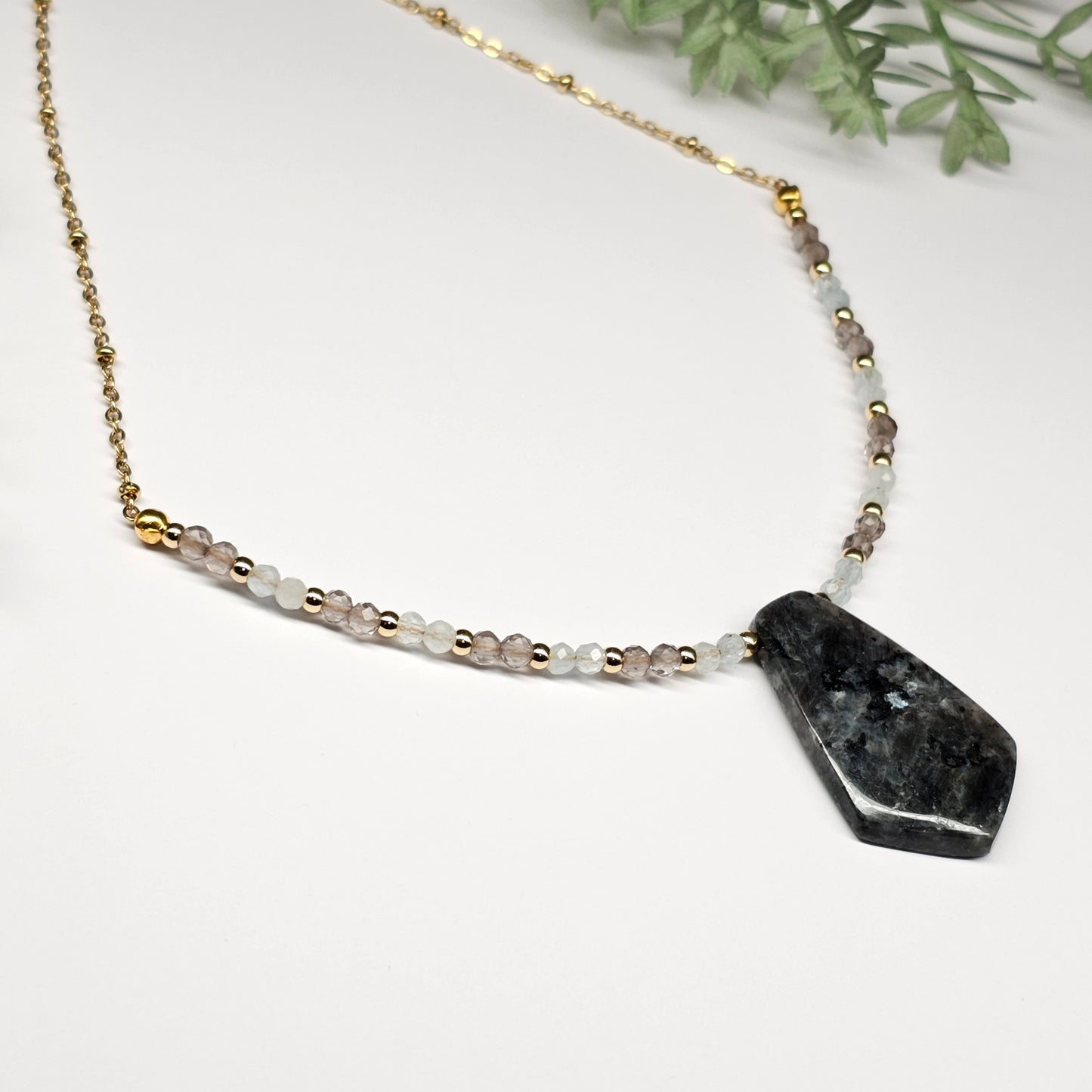 Lunar bloom is a focal Larvikite pendant necklace adorned with Smoky Quartz and Aquamarine beads.