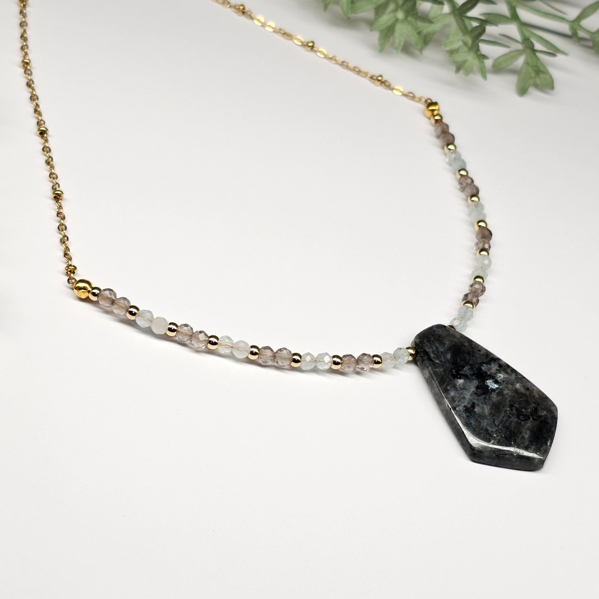 Lunar bloom is a focal Larvikite pendant necklace adorned with Smoky Quartz and Aquamarine beads.