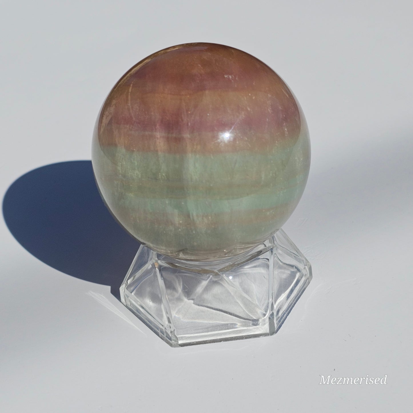 Rainbow Fluorite sphere banded with an array of colours, including a display of beautiful rainbows.