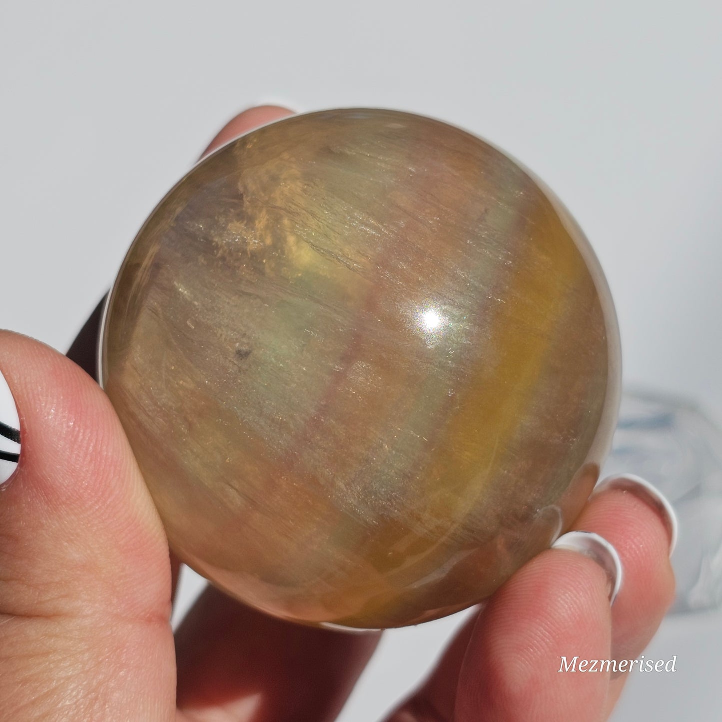 Yellow rainbow Fluorite sphere banded with an array of colours, including a display of beautiful rainbows.