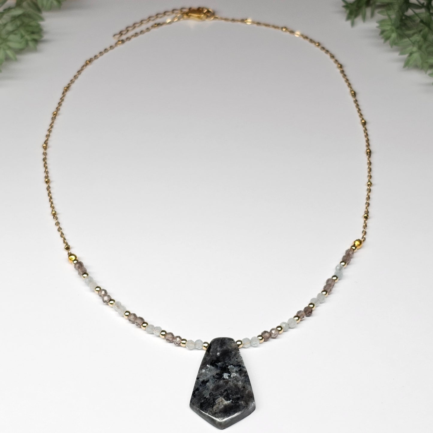 Lunar bloom is a focal Larvikite pendant necklace adorned with Smoky Quartz and Aquamarine beads.