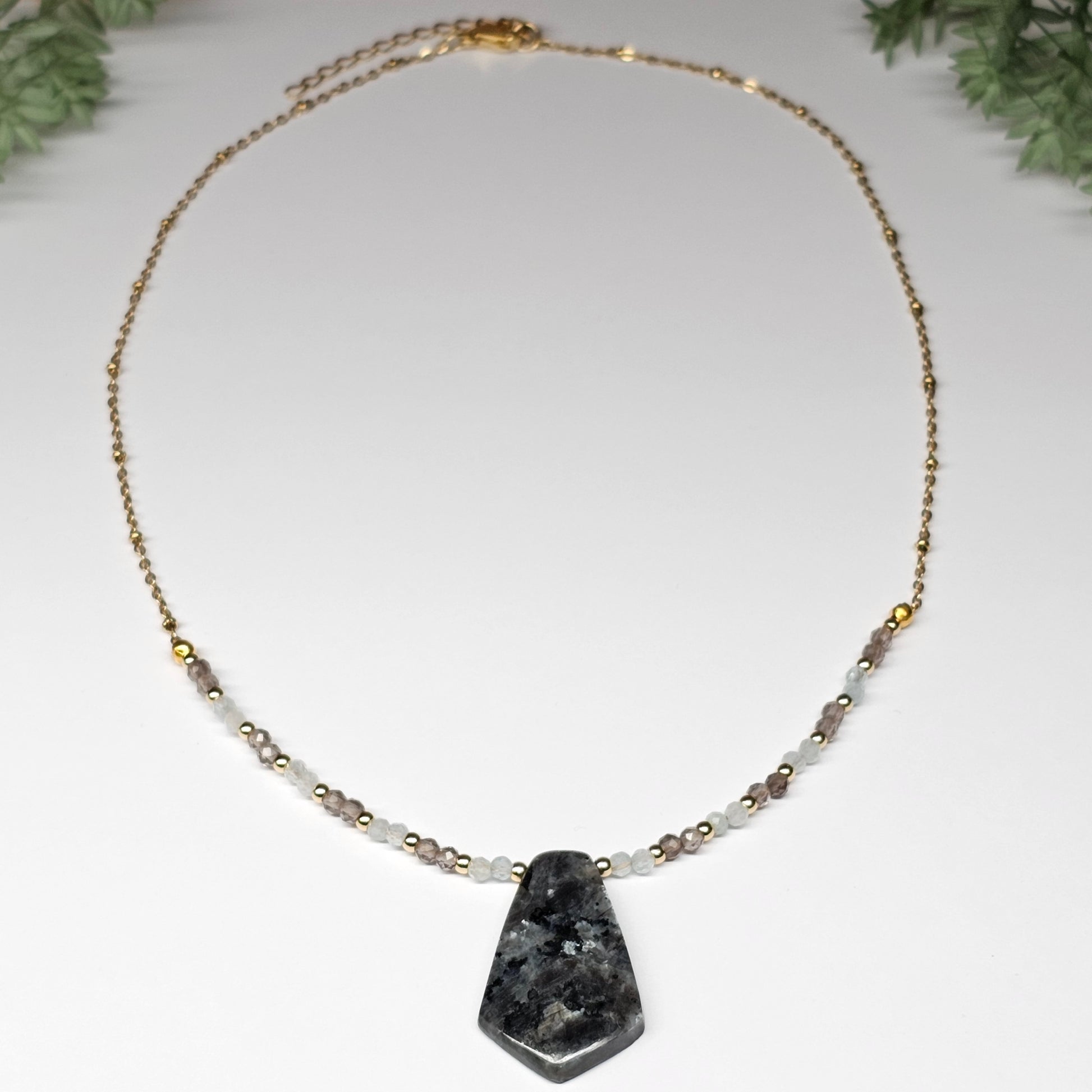 Lunar bloom is a focal Larvikite pendant necklace adorned with Smoky Quartz and Aquamarine beads.
