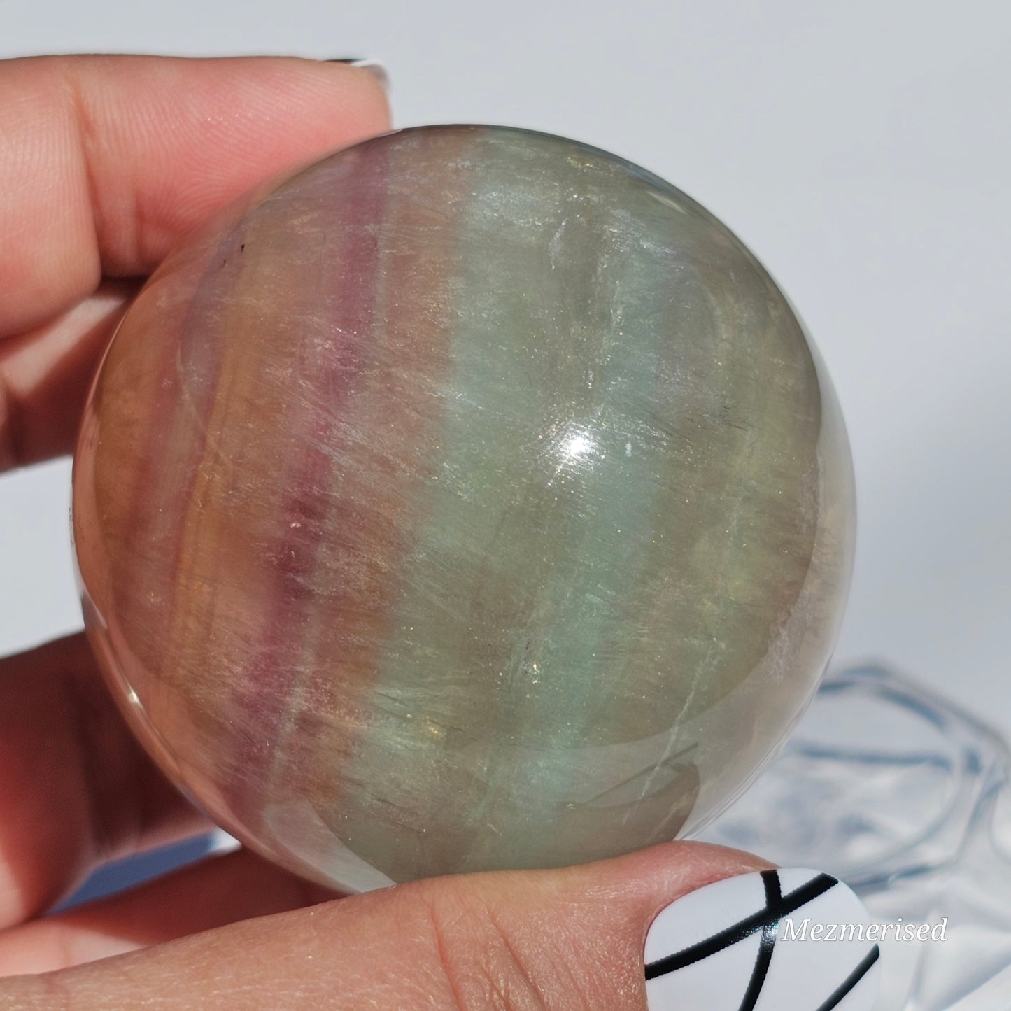 Rainbow Fluorite sphere banded with an array of colours, including a display of beautiful rainbows.